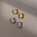 Two pairs of Hammered Rectangle Hoops, one gold and one silver, showcase a geometric design and textured finish, displayed on a neutral background with soft shadows.