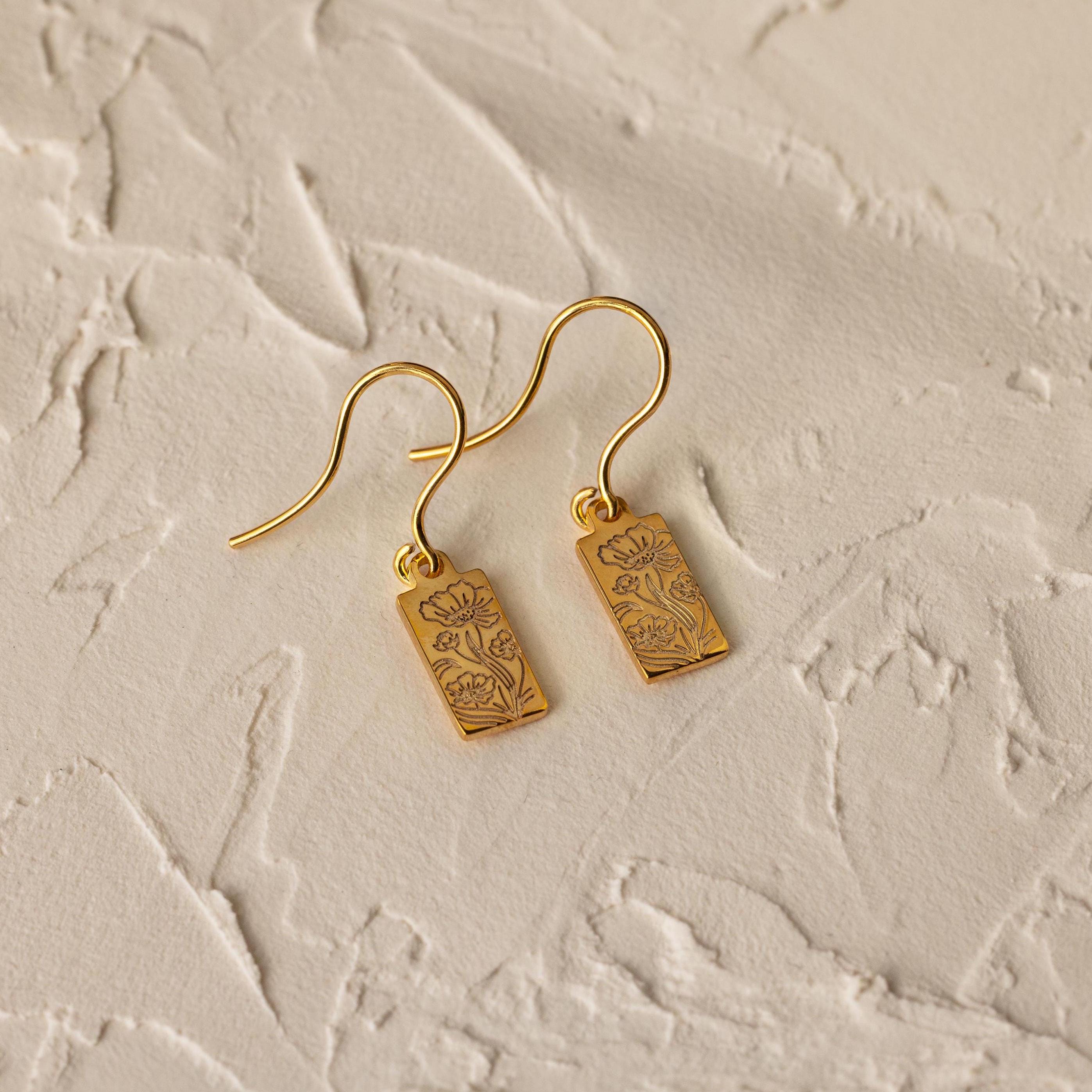 Rectangle Birth Flower Earrings featuring delicate floral engravings, perfect for personalizing your flower jewelry collection. Shown on a textured beige surface.
