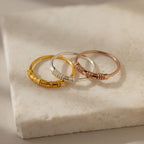 Three Dainty Morse Code Rings in gold, silver, and rose gold—ideal as personalized jewelry or a custom initial ring—are displayed on a white marble surface.