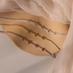 A Mama Tennis Letter Bracelet with gold letters spelling MAMA rests on a beige fabric background—an ideal example of customized jewelry, perfect for stylish gift giving.