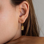 Close-up of a woman's ear wearing Rectangle Birth Flower Earrings—gold rectangular earrings with a floral design, ideal for fans of flower jewelry and personalized accessories.
