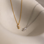 The Pearl Diamond Drop Necklace, along with other gold and silver bridal necklaces featuring pearl and crystal pendants, is displayed on a smooth beige surface.