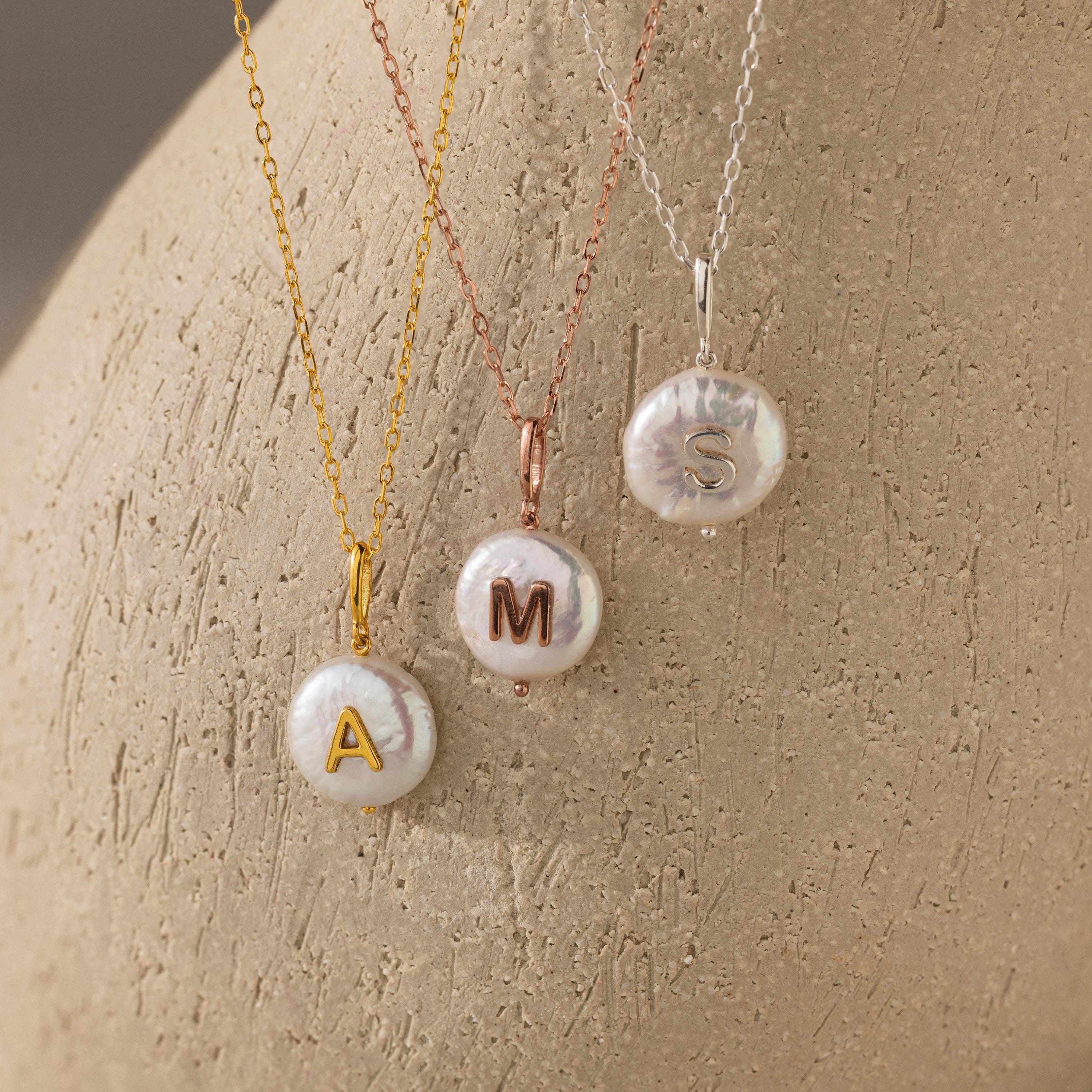 The Pearl Initial Pendant Necklace features a freshwater pearl on your choice of gold, rose, or silver chain, each with a personalized initial pendant—A, M, or S—for a unique accessory.
