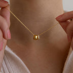 Close-up of a person holding a dainty Pave Duo Circle Necklace with two pendants near their neck, paired with a light sweater.