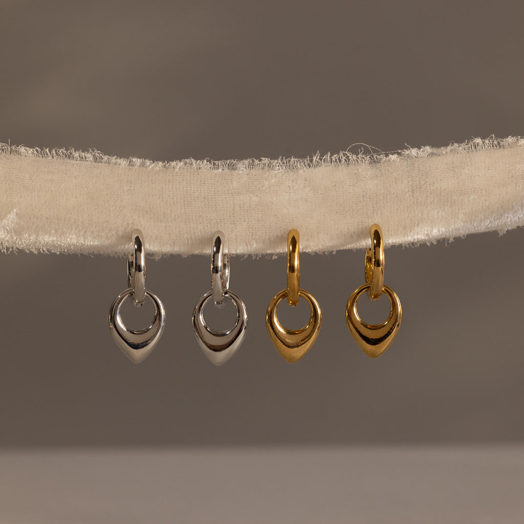 Two silver and two gold heart-shaped charms hang on a textured, off-white fabric string—perfect for pairing with your favorite Bold Teardrop Hoops for a charming, coordinated look.