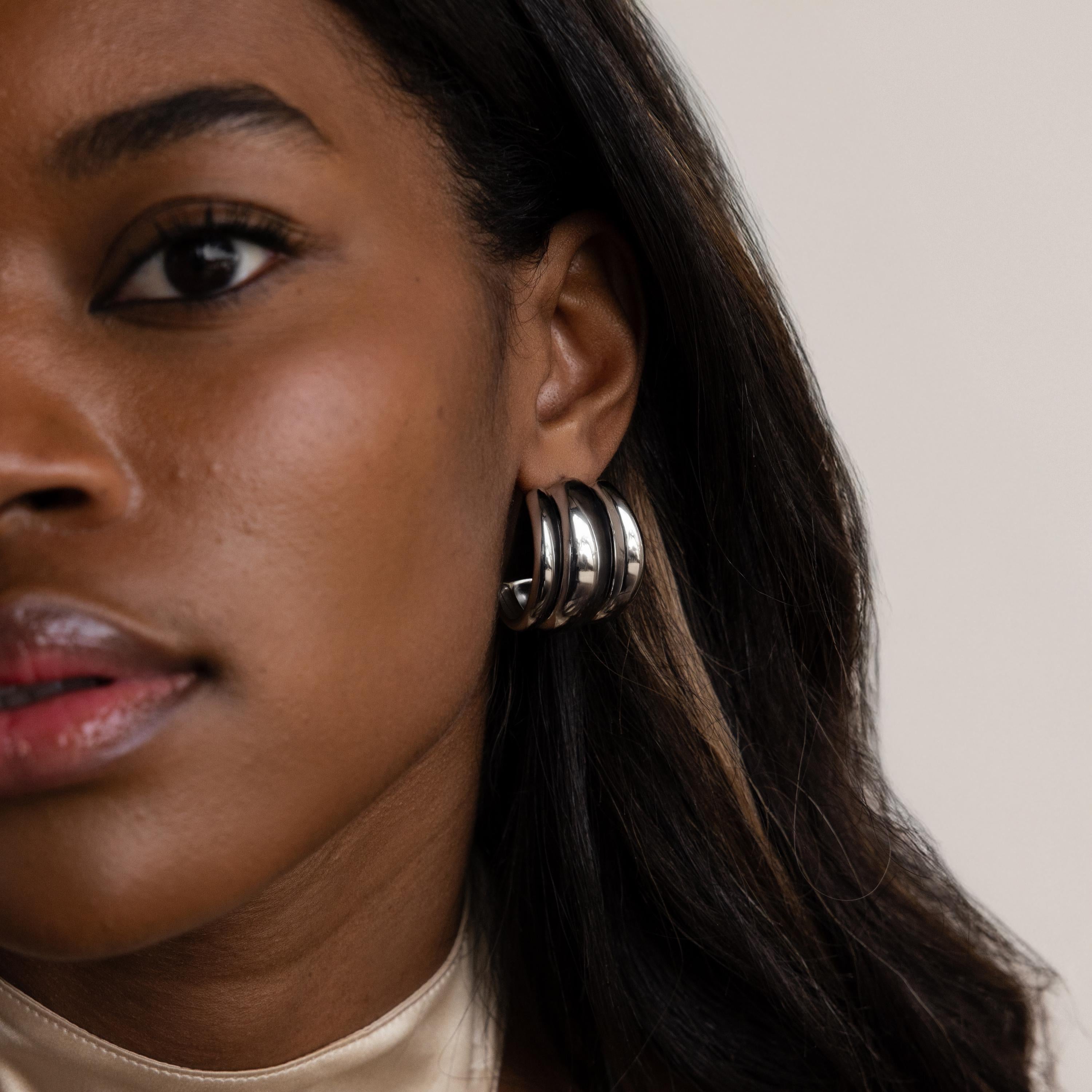 Close-up of a woman in a cream-colored top wearing Chunky Triple Hoops, showcasing bold statement earrings.
