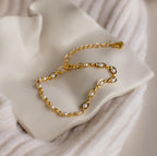 The Eternity Pearl Bracelet is elegantly displayed on a white ceramic dish with a soft textured fabric background.