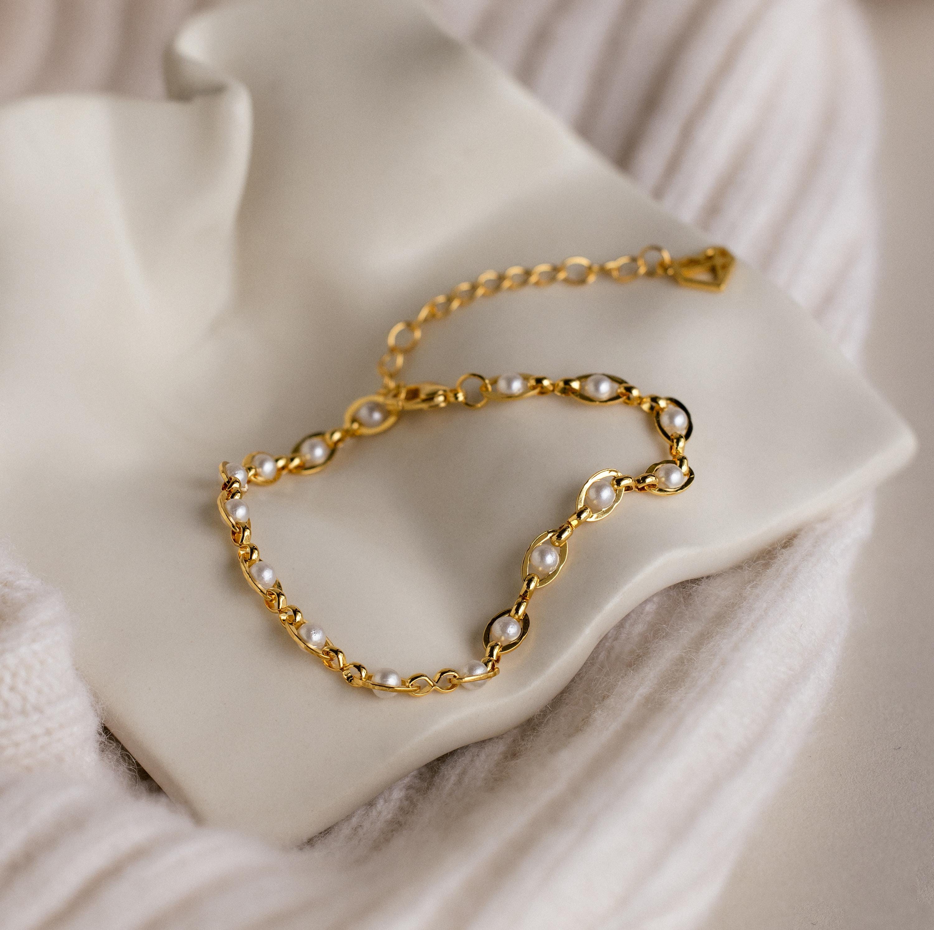 The Eternity Pearl Bracelet is elegantly displayed on a white ceramic dish with a soft textured fabric background.