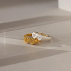 Two Duo Initial Heart Rings, one gold and one silver, both showcasing a heart-shaped design, rest elegantly on a light surface.