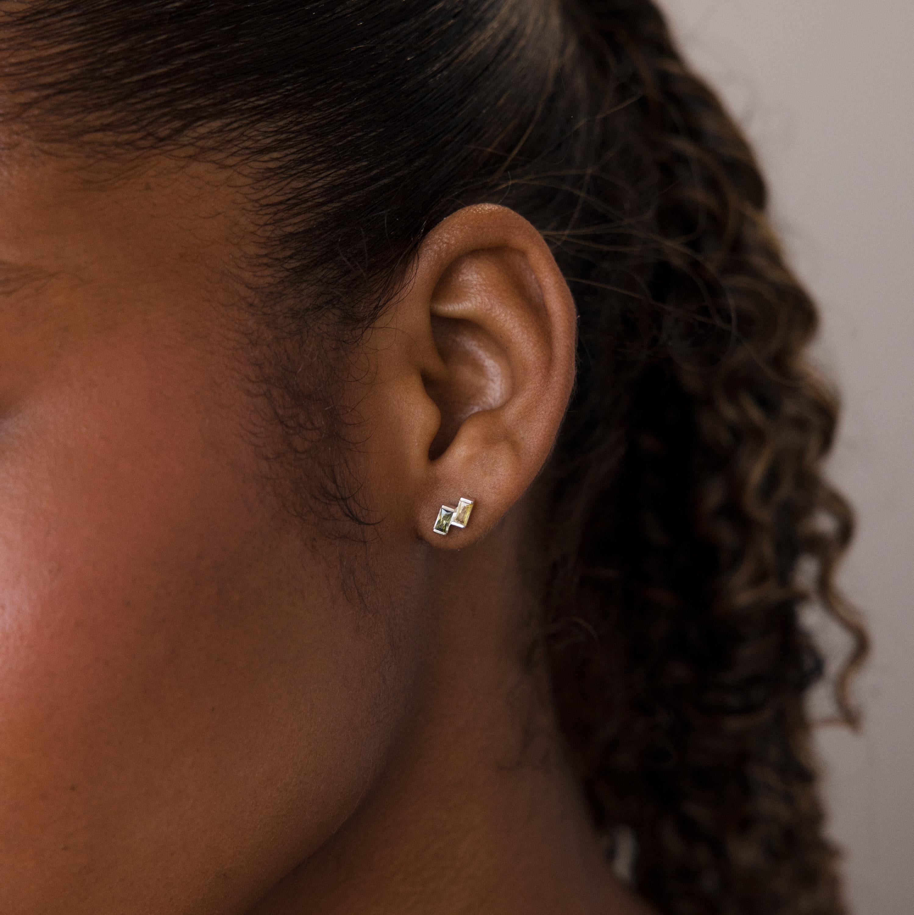 Close-up of a woman's ear wearing Duo Baguette Birthstone Studs, her curly hair pulled back to showcase the personalized geometric jewelry.