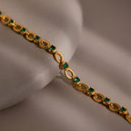 Emerald Chain Tennis Bracelet showcased on a smooth, light beige surface.