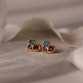 Mixed Birthstone Heart Studs with customizable gemstones, shown on a soft, neutral fabric background.
