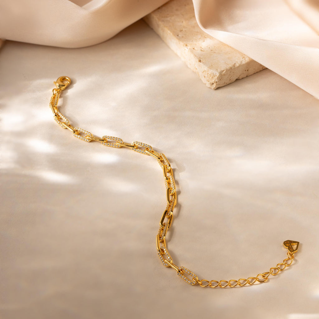 The Pave Paperclip Chain Bracelet features delicate, sparkling details and is displayed on a light, textured surface.