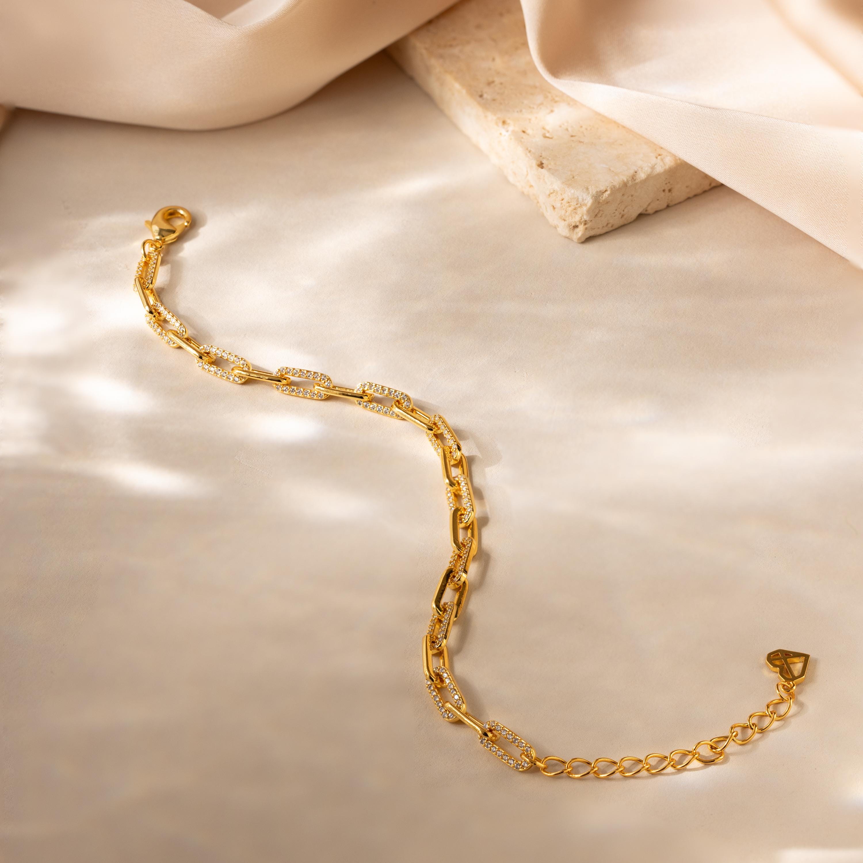 The Pave Paperclip Chain Bracelet features delicate, sparkling details and is displayed on a light, textured surface.