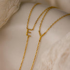 Two Initial Birthstone Lariat Necklaces with E and Y pendants are displayed on a light fabric background, offering personalized jewelry as unique initial birthstone necklaces.