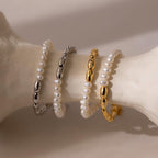 The Duo Beaded Pearl Bracelet, featuring layers of pearls and metallic beads, rests on a white curved surface in soft lighting.