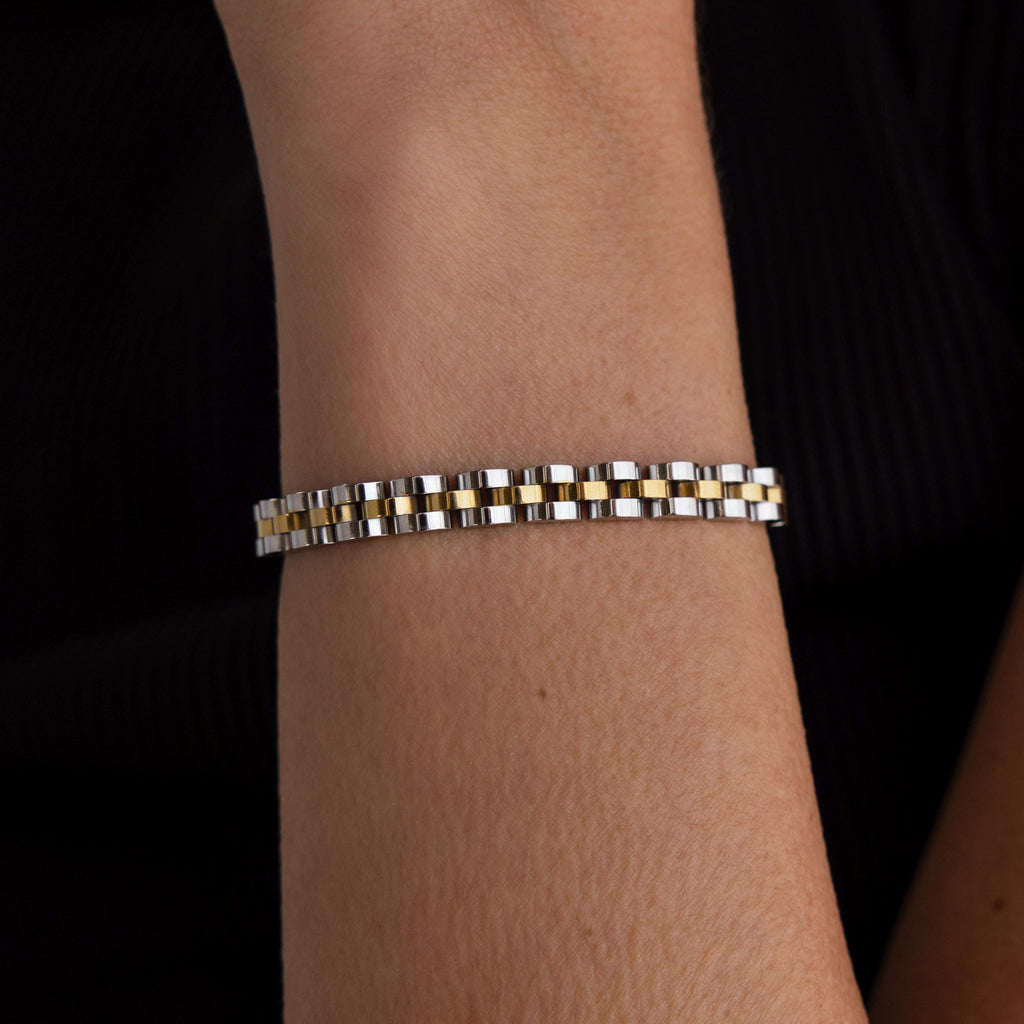 The Mixed Metal Link Bracelet, crafted in silver and gold, is shown on a wrist against a black background—an ideal gift for him.
