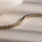 A close-up of the Mixed Metal Link Bracelet showcases its silver and gold design, making it a stylish gift for him. Displayed on a light surface.
