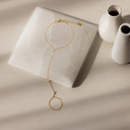 The Pearl Hand Chain Bracelet is shown with pearls on a white stone next to two small white vases, adding a touch of summer elegance.