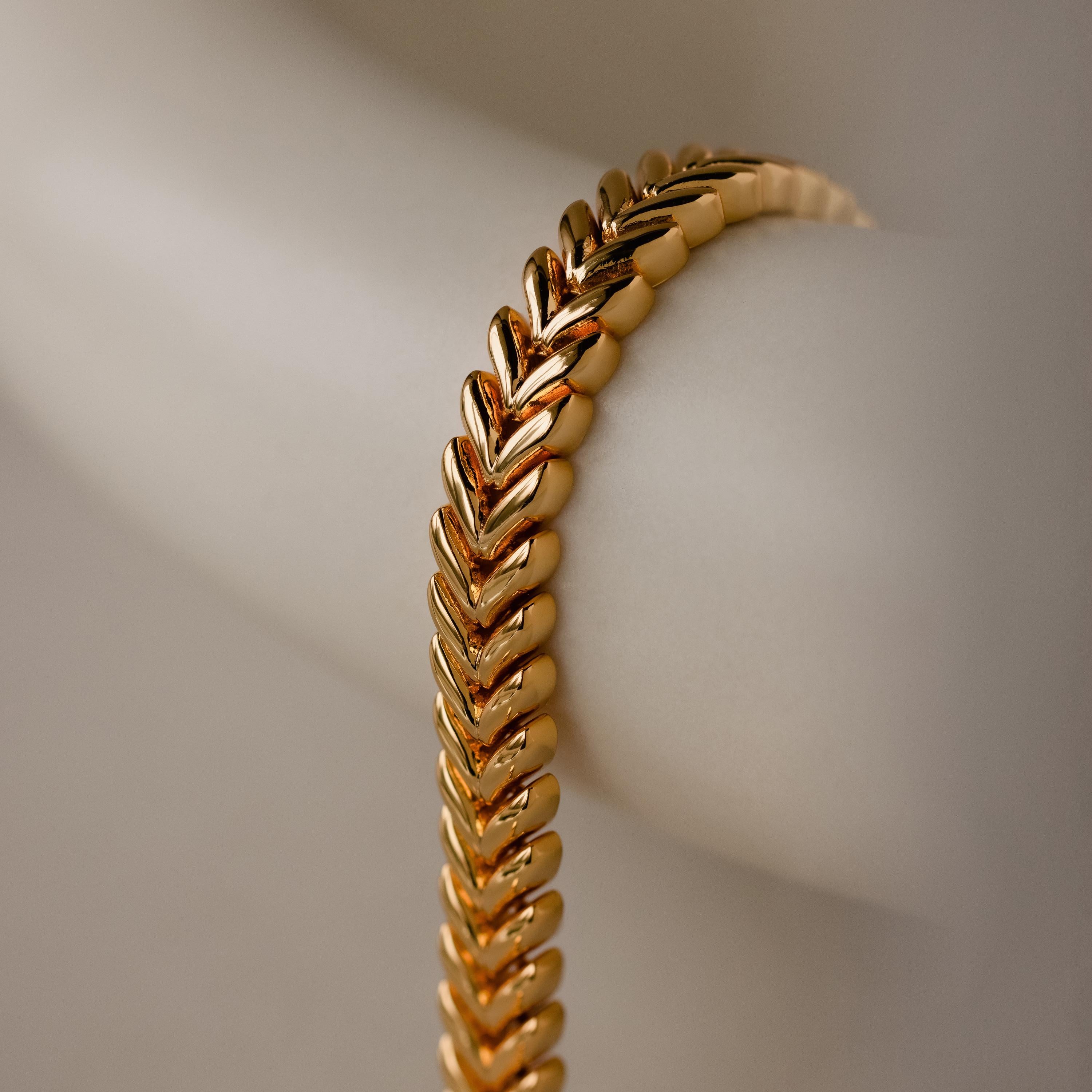 A close-up of the V-Link Chain Tennis Bracelet, featuring sculptural gold links, displayed on a light-colored surface.