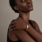 Woman in a sleeveless top showcases the Dome Cuff Bracelet, resting one hand on her opposite shoulder for a stylish accent.