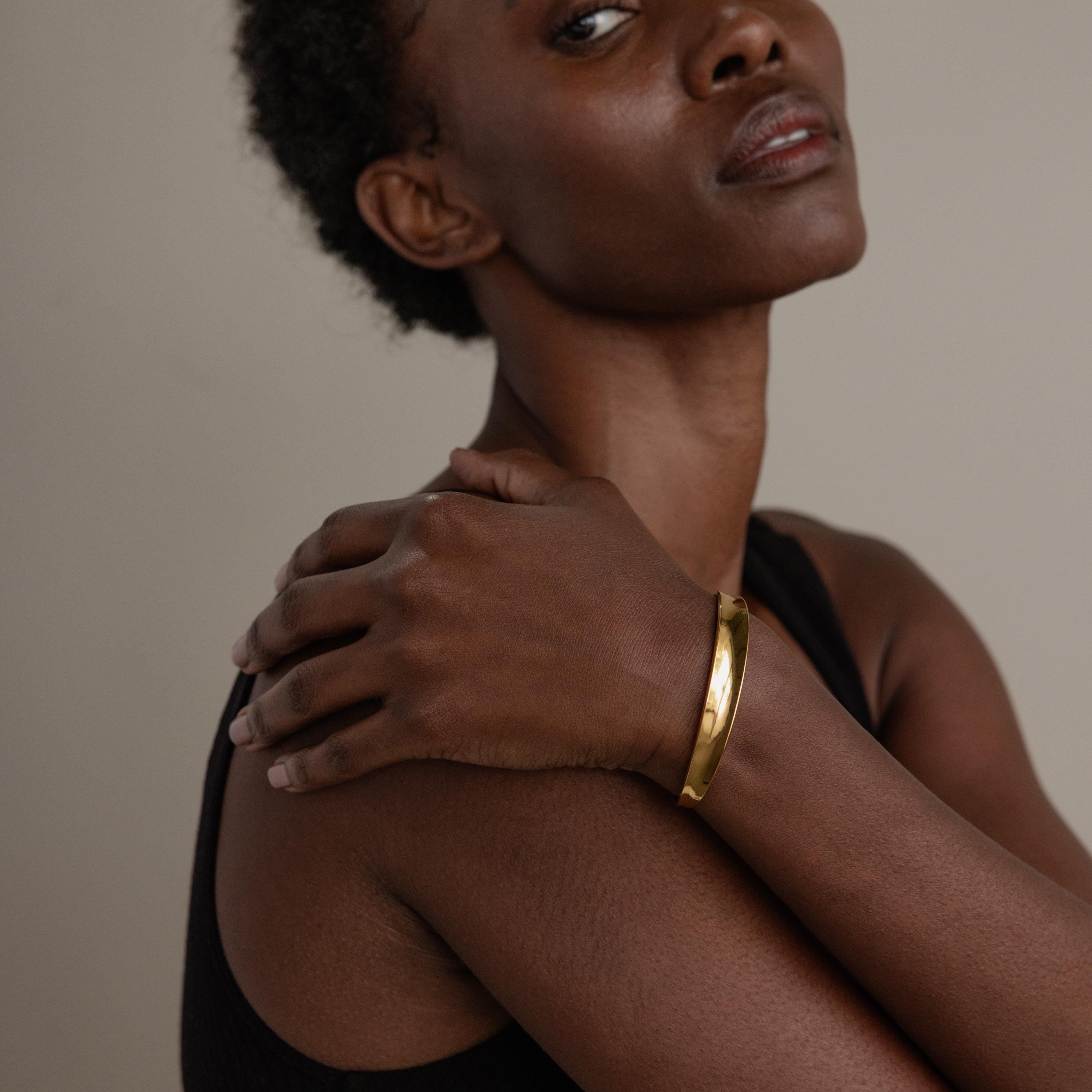Woman in a sleeveless top showcases the Dome Cuff Bracelet, resting one hand on her opposite shoulder for a stylish accent.