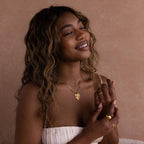 Model wears a gold vintage heart charm on a curb necklace, posing with other gold jewelry