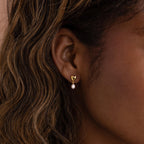 A close-up of a woman's ear wearing the Heart Pearl Drop Earrings.