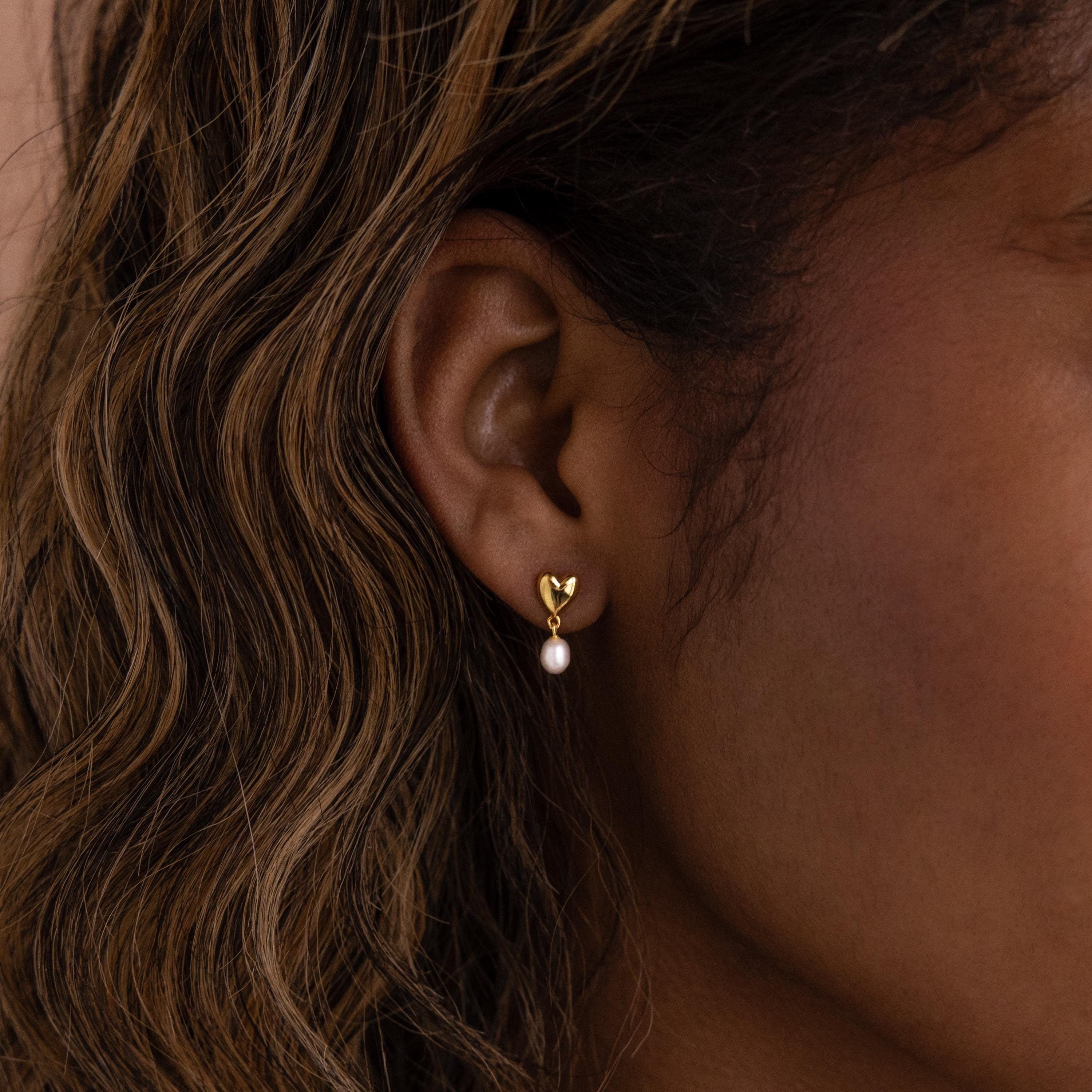 A close-up of a woman's ear wearing the Heart Pearl Drop Earrings.