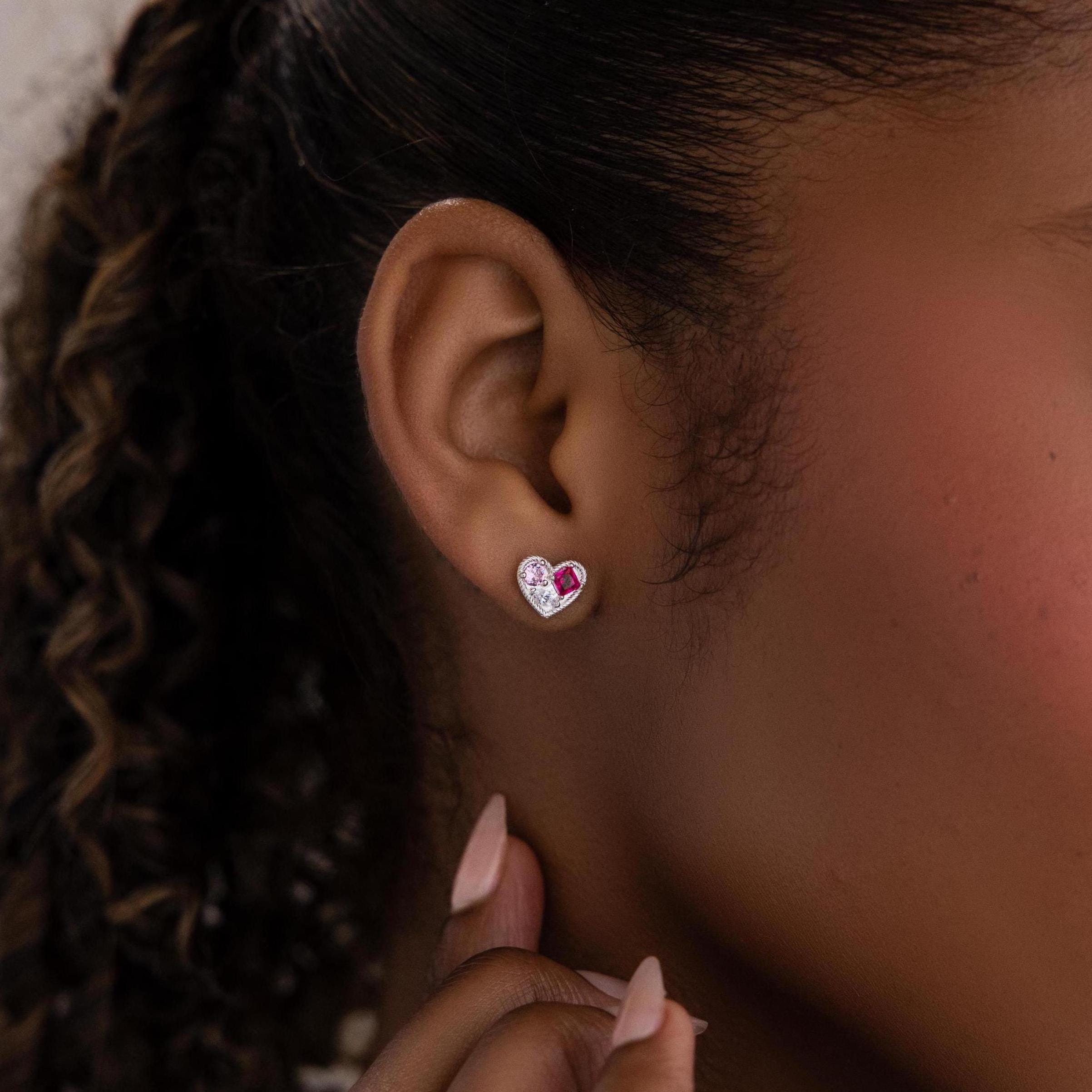 Close-up of a woman's ear wearing Mixed Birthstone Heart Studs, elegant earrings with silver and pink accents and customizable birthstones.