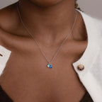 Model wears silver cable chain with aquamarine pear birthstone charm and blue zircon baguette birthstone charm