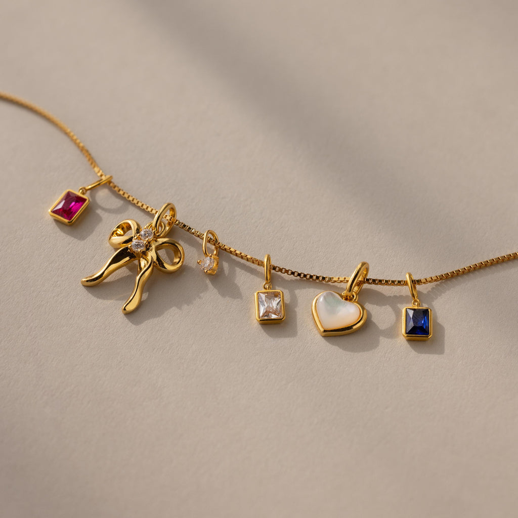 An assortment of charms laid out on a gold box chain.