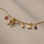 An assortment of charms laid out on a gold box chain.
