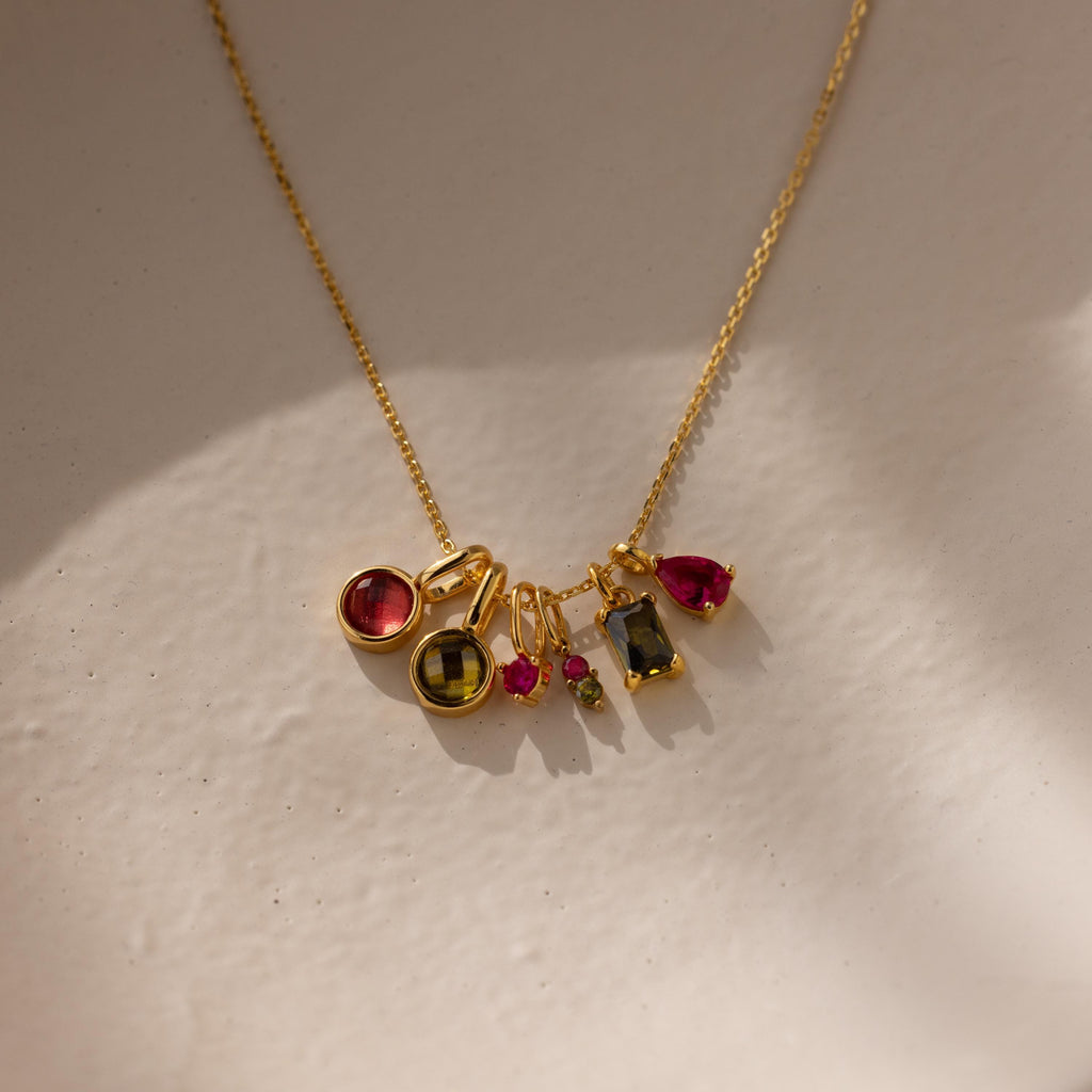 Several different types of birthstone charms on a gold cable chain