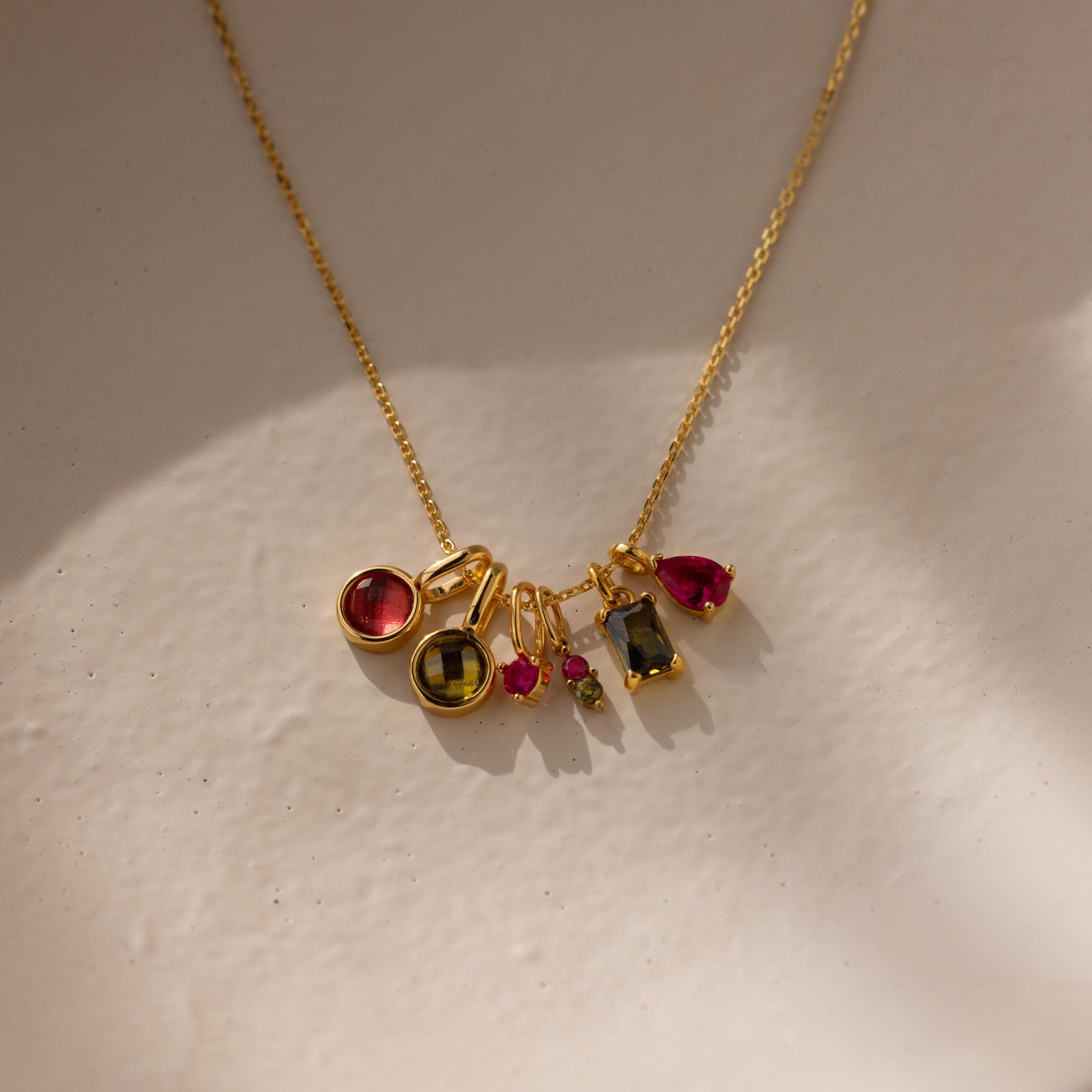 Several different types of birthstone charms on a gold cable chain