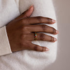 A hand wearing a Vintage Multiple Birthstone Ring with colorful gemstones rests on a light sweater.