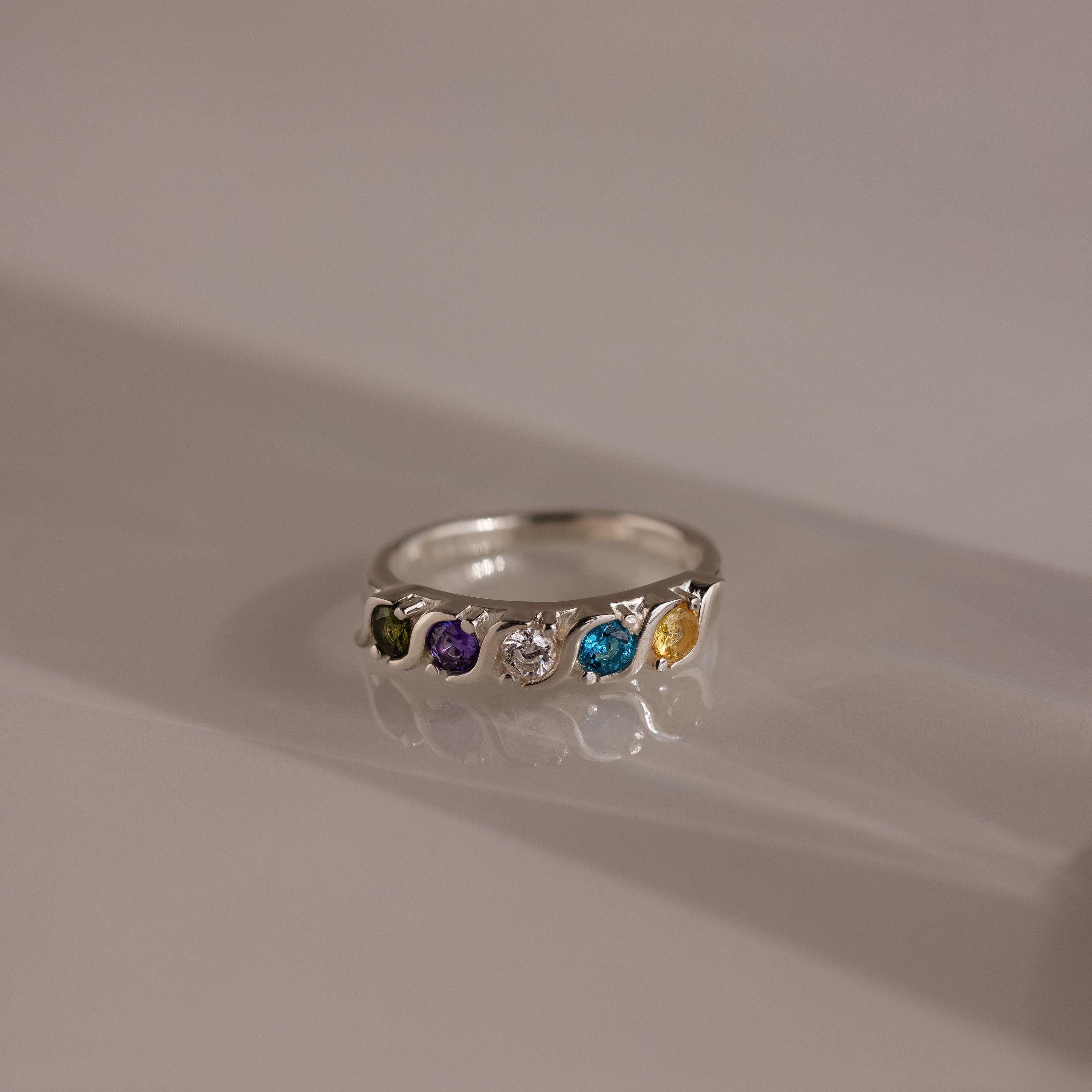 The Vintage Multiple Birthstone Ring showcases five vibrant gemstones set in a row on a sleek, neutral band.