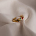 Vintage Multiple Birthstone Ring featuring four colorful gemstones displayed on soft, beige fabric.
