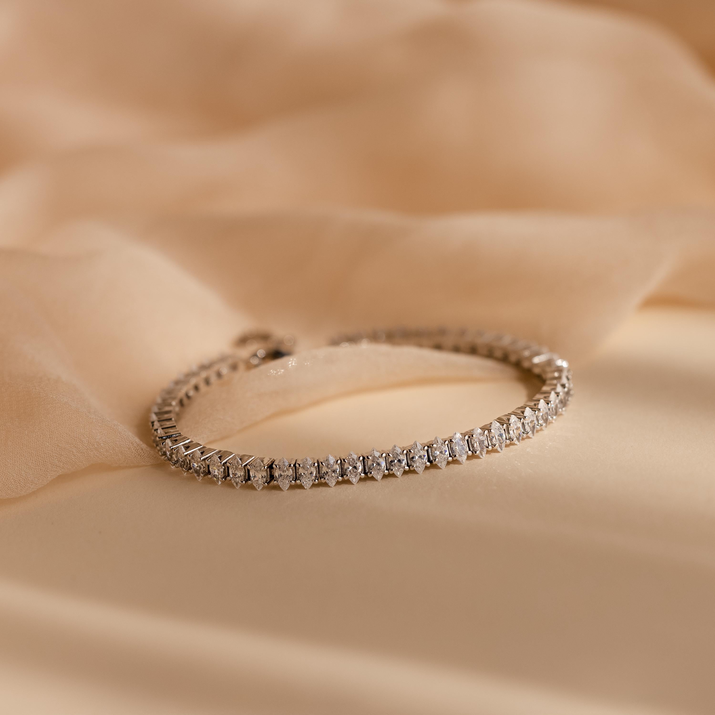 Close-up of the Marquise Diamond Tennis Bracelet in silver, featuring a continuous row of marquise-cut diamonds set in a sleek silver band, displayed on a soft beige fabric.
