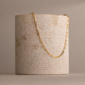 The Bold Paperclip Chain Necklace features rectangular links draped over a textured, cylindrical beige stone—a striking statement piece for any look.