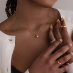 Model wearing a gold Singapore Twist Necklace with Pear & Baguette Birthstone Charm Set, completing the look with gold rings