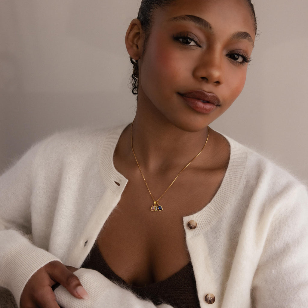 Model wears gold box chain with three different emerald birthstone charms in pink tourmaline, diamond and sapphire