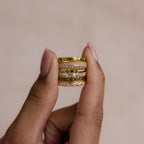Hand holding a stack of gold peridot and diamond rings, showing the detailed stone settings.