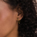Close-up of a woman's ear wearing Agate Diamond Chain Earrings featuring a gold chain connecting a green moss agate stud and a classic diamond stud for an elegant, modern look.
