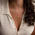 A woman wears a textured cream blouse and our Mixed Diamond Lariat Necklace, featuring small diamond gemstones for subtle sparkle.