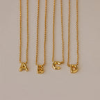 Four Dainty Bubble Letter Necklaces in 18K Gold, featuring A, B, C, and D pendants, displayed on a neutral background—ideal for a minimalist personalized accessory.