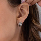 Close-up of a woman's stacked ear wearing Triple Loop Huggie Earrings—sleek, silver hoops designed for everyday style.