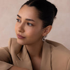 Woman with dark hair in a bun, wearing a beige blazer and Bold Duo Knot Earrings, looking to the side.