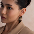 A woman wearing Bold Duo Knot Earrings and a beige blazer, gazing slightly to the left against a soft background.