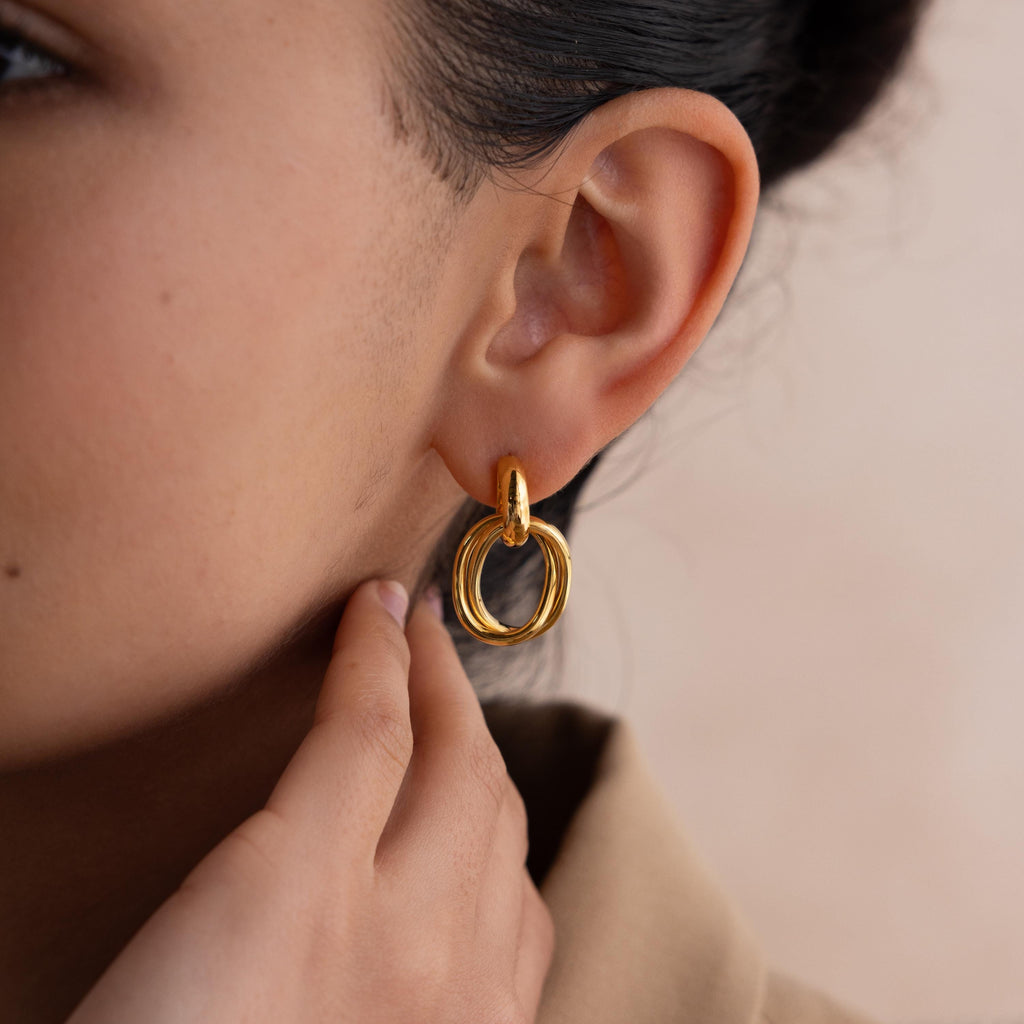 Close-up of a person wearing the Bold Duo Knot Earrings, touching their earlobe with their hand.